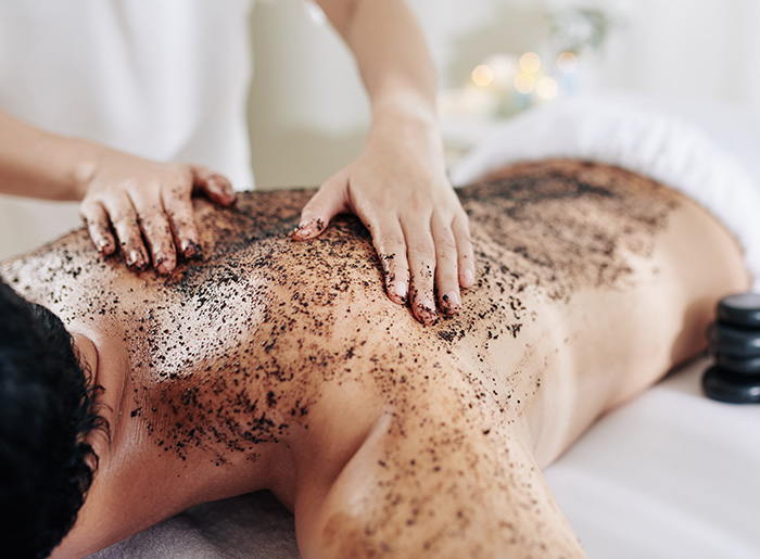 cosmetologist-applying-coffee-peeling_klein Männerrücken wird mit Kaffeescrub behandelt