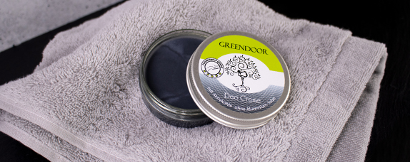 GREENDOOR Fußcreme auf grauem Handtuch Dose mit GREENDOOR Fußcreme, geöffnet auf einem grauen Handtuch