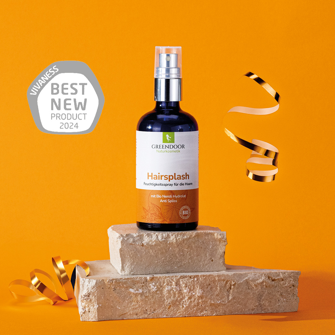 Produktfotos_Hairsplash_web_2_(1) Greendoor Hairsplash Flasche steht auf Steinsockel zusammen mit Siegel Best New Product 2024